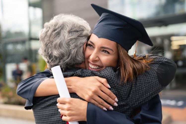 Portrait of a happy student hugging her father and celebrating her graduation - education concepts